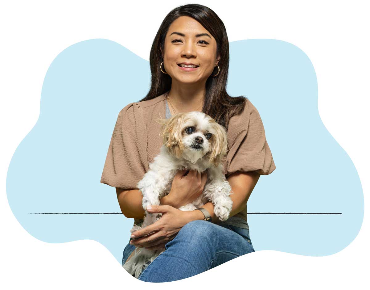 20250423_026 A woman in a brown shirt sitting with her white dog in her lap