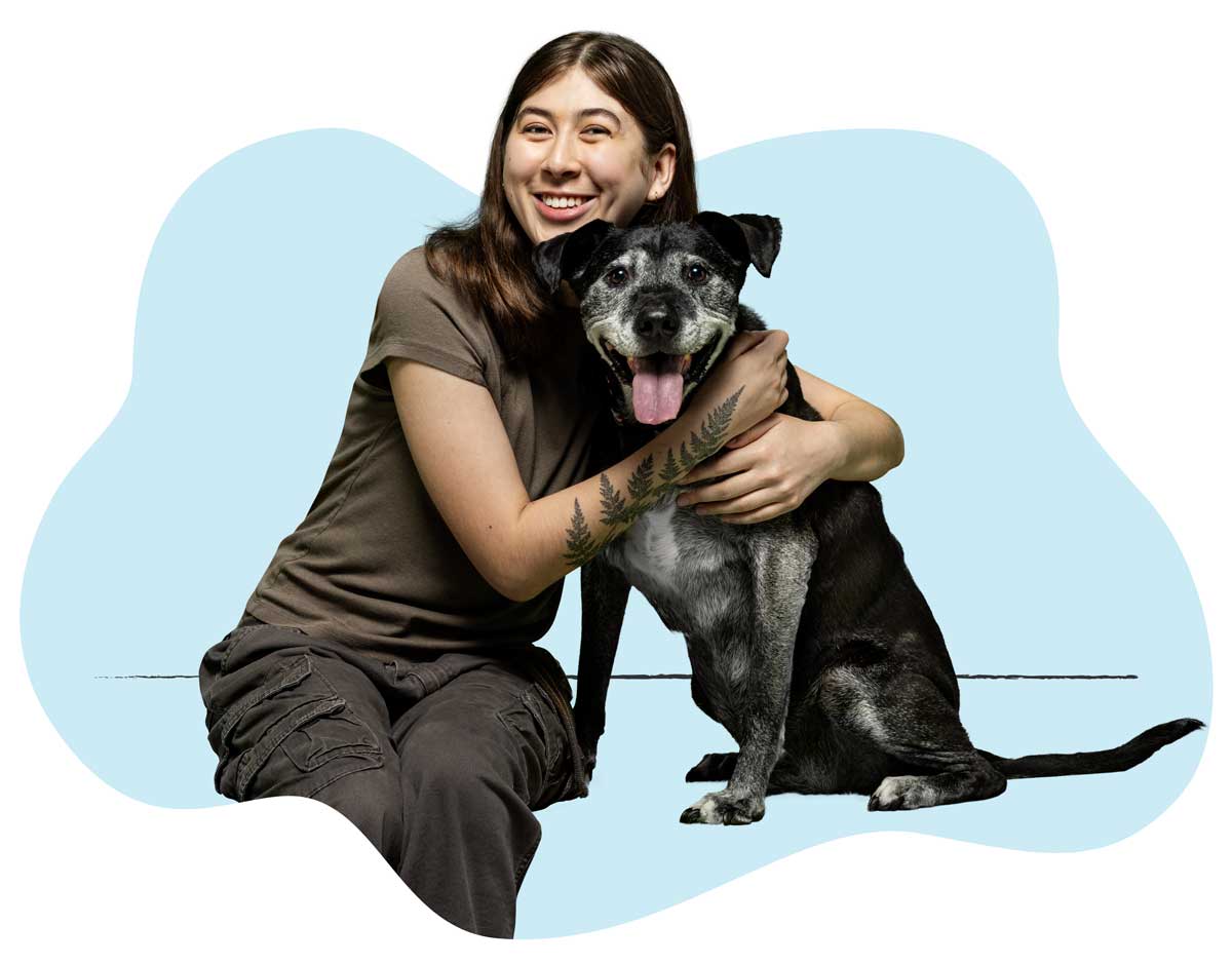 20250423_027 A woman in a brown shirt sitting on the floor hugging her black-haired dog