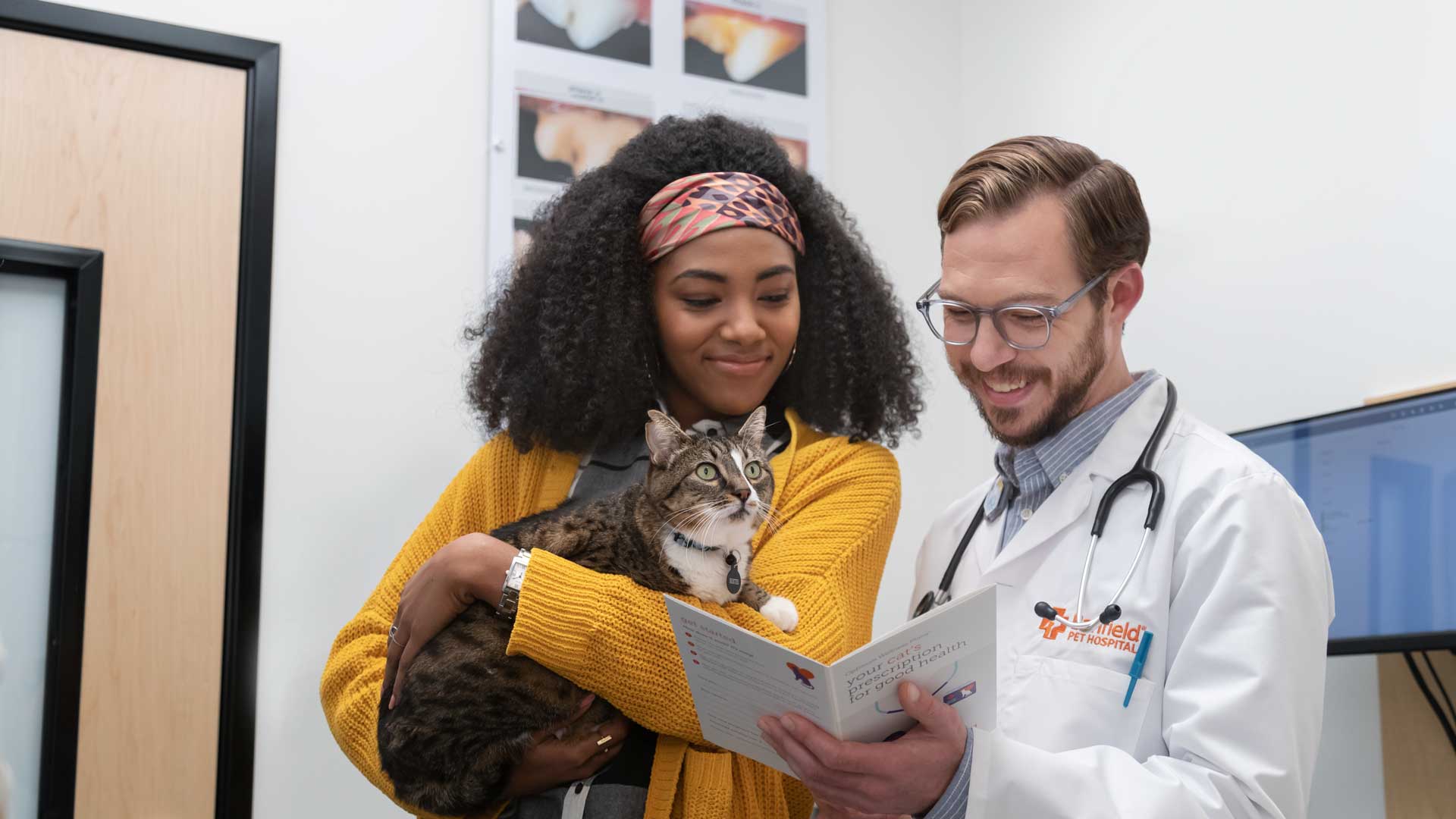 A pet owner holding her cat next to a Banfield veterinary professional 