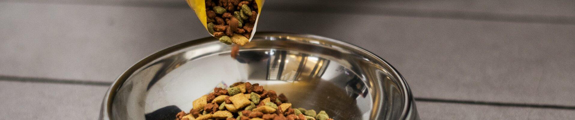 Pet food being poured into a metal bowl