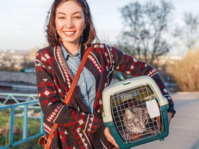 A woman carrying her cat in a carrier