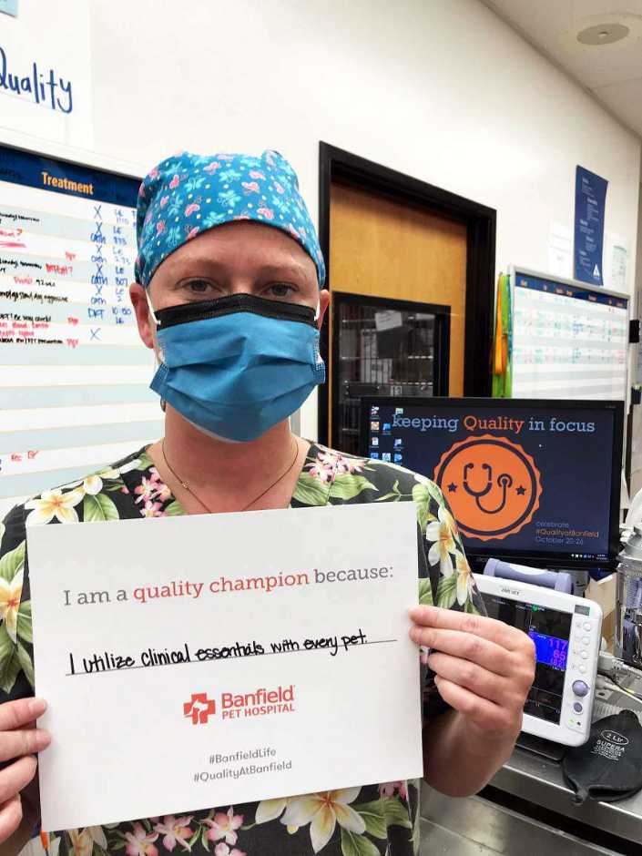 A young female associate holding a placard at the Banfield Pet Hospital