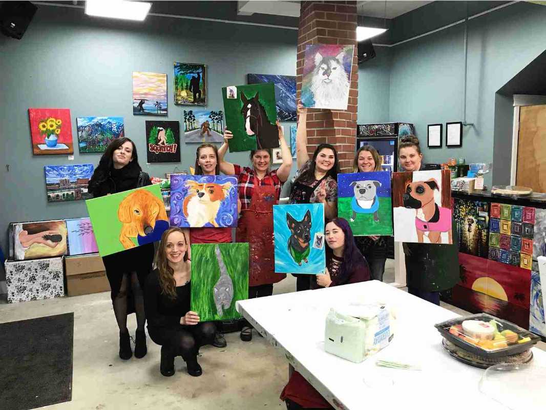 A group of associates holding pet animal paintings at the Banfield Pet Hospital